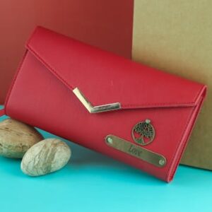 Elegant red wallet featuring a metal tree emblem and 'Love' inscription, posed on a turquoise and red background.