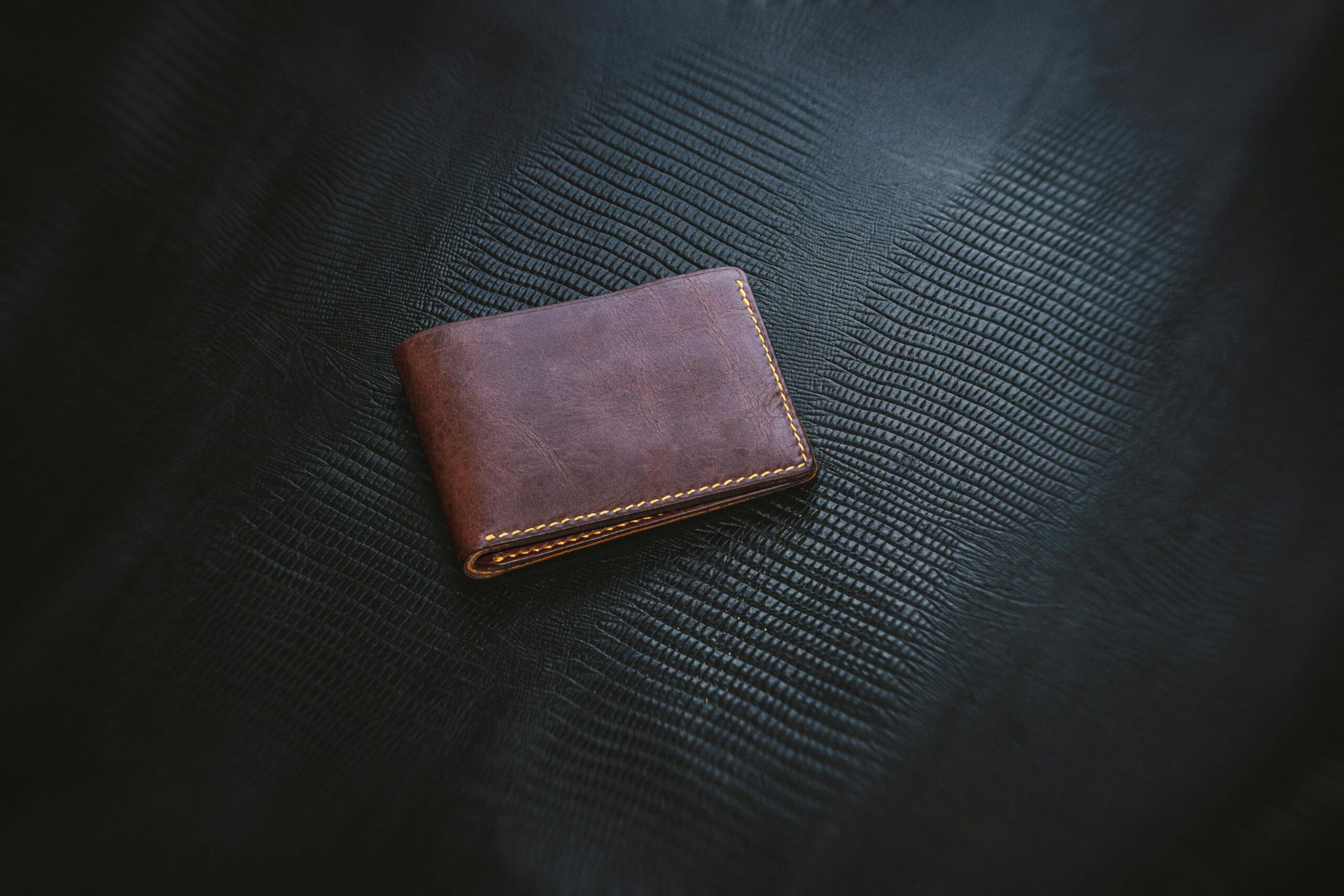 Elegant brown leather wallet showcasing minimalist design on a textured surface. Perfect for fashion and lifestyle themes.