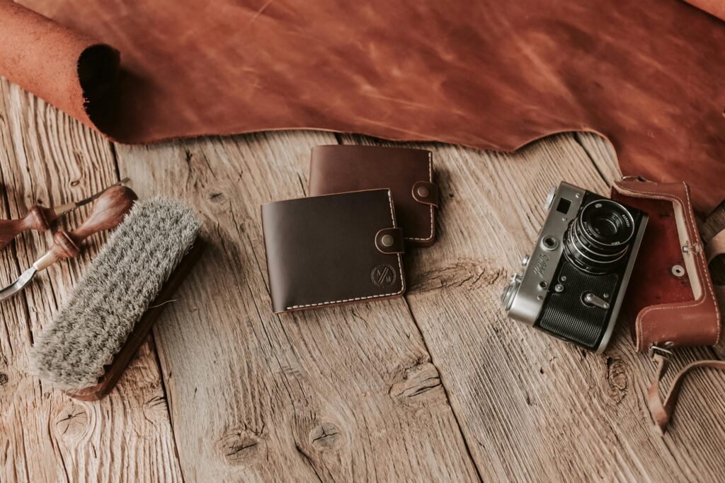 Capture the essence of craftsmanship with leather wallets and a vintage camera on rustic wood.